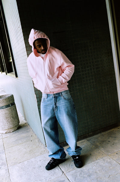 Model wearing the baby pink Drama Call STA zip-up hoodie in a lifestyle view.