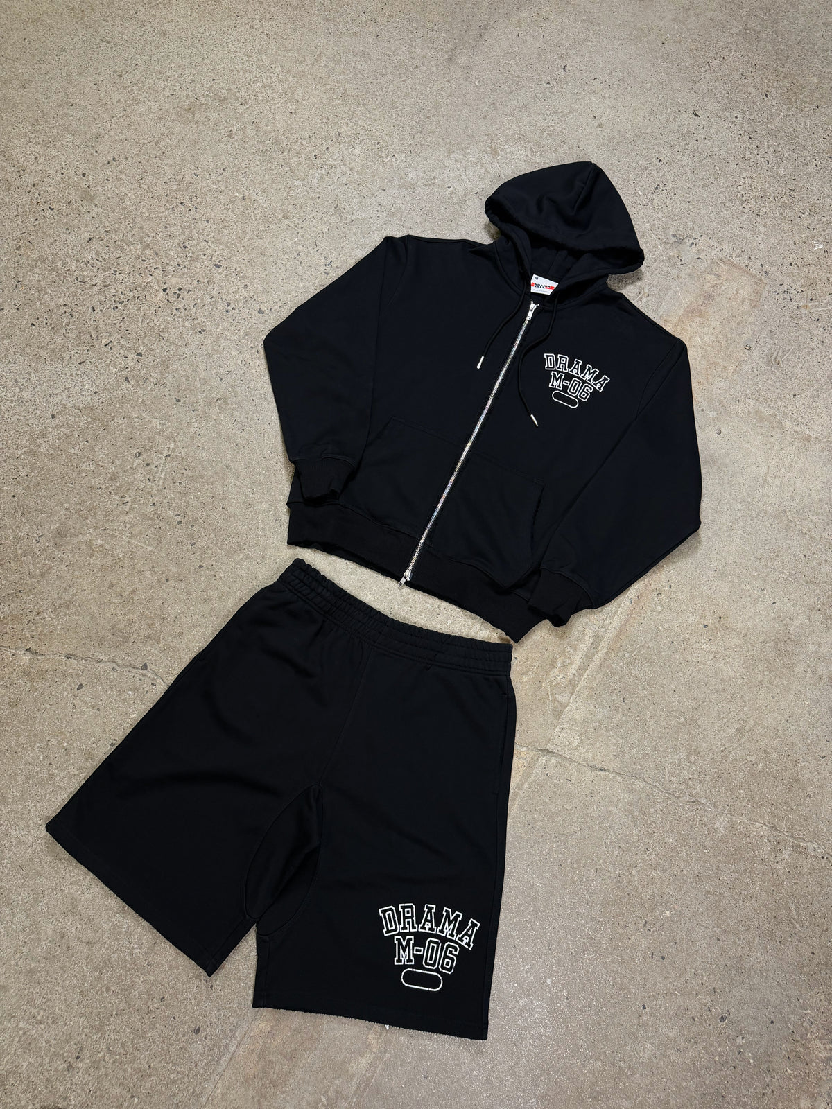 Men's black Drama Call distressed college zip-up hoodie and shorts set, flat lay view.
