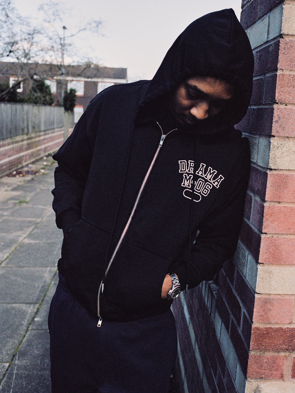 Model wearing a black distressed college zip-up hoodie, lifestyle view