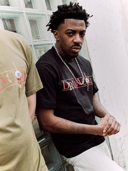 Lifestyle shot of a model wearing the Drama Call Nevercall black graphic tee
