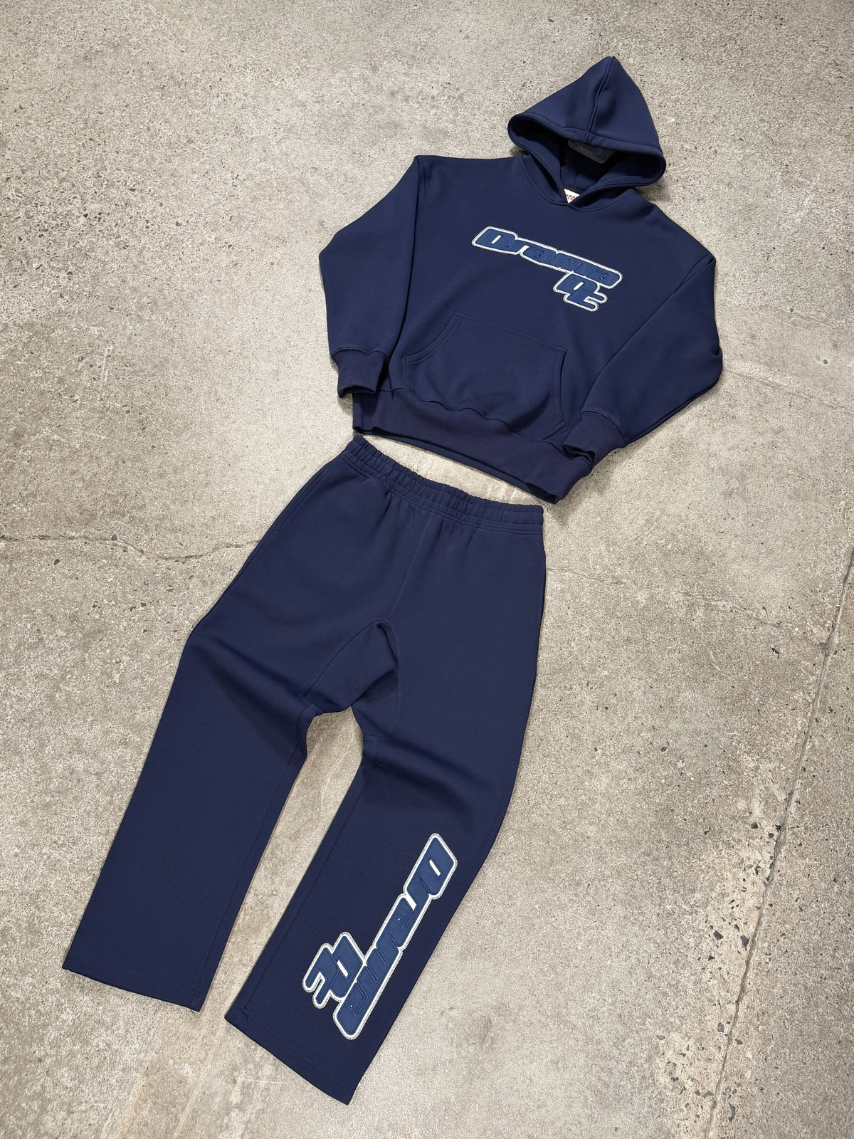 Men's navy AV sport hoodie and matching sweatpants set laid out flat